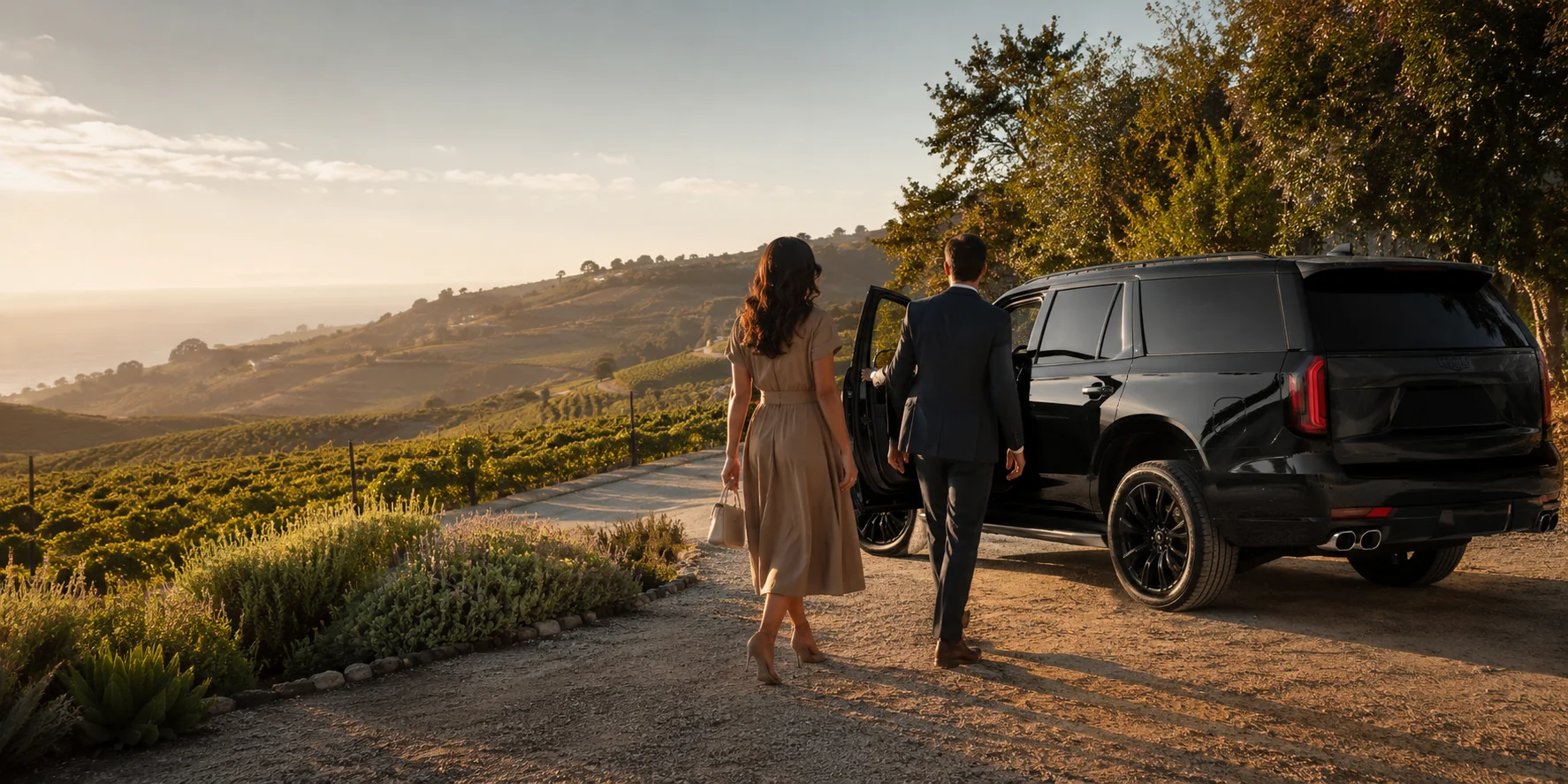Guests approaching a black luxury SUV beside a sunlit Southern California hillside vineyard